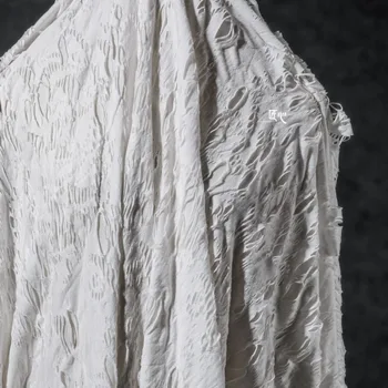 Белое отверстие, потрескавшееся и порванное эластичное трикотажное полотно, творческая реконструкция текстуры дизайнерской ткани для одежды ручной работы